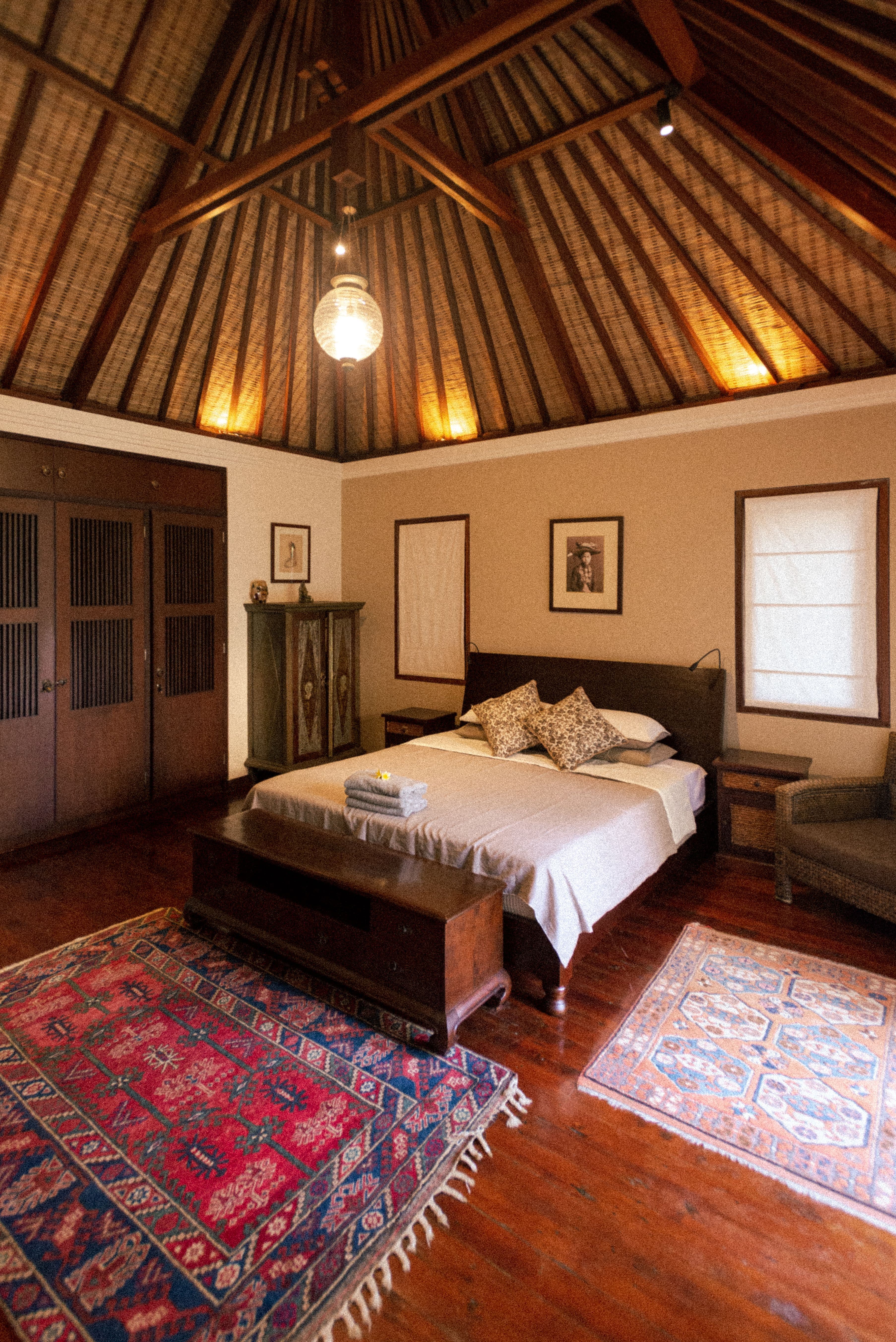 Furnished bedroom with a wooden bed, bedside tables, rugs and a vaulted timber ceiling; illustrative stock interior, not an Embrace development.